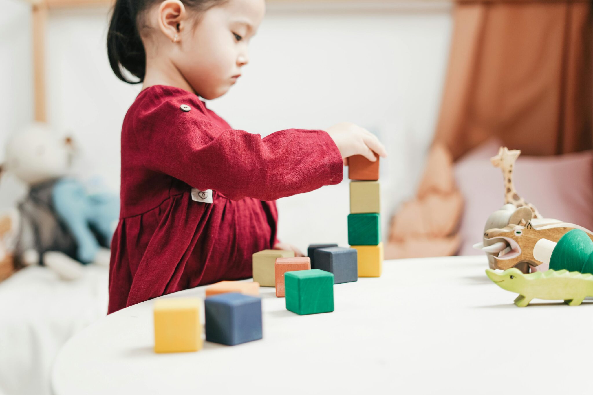 A young girl engaging with colorful wooden blocks, fostering creativity and learning in a playroom.