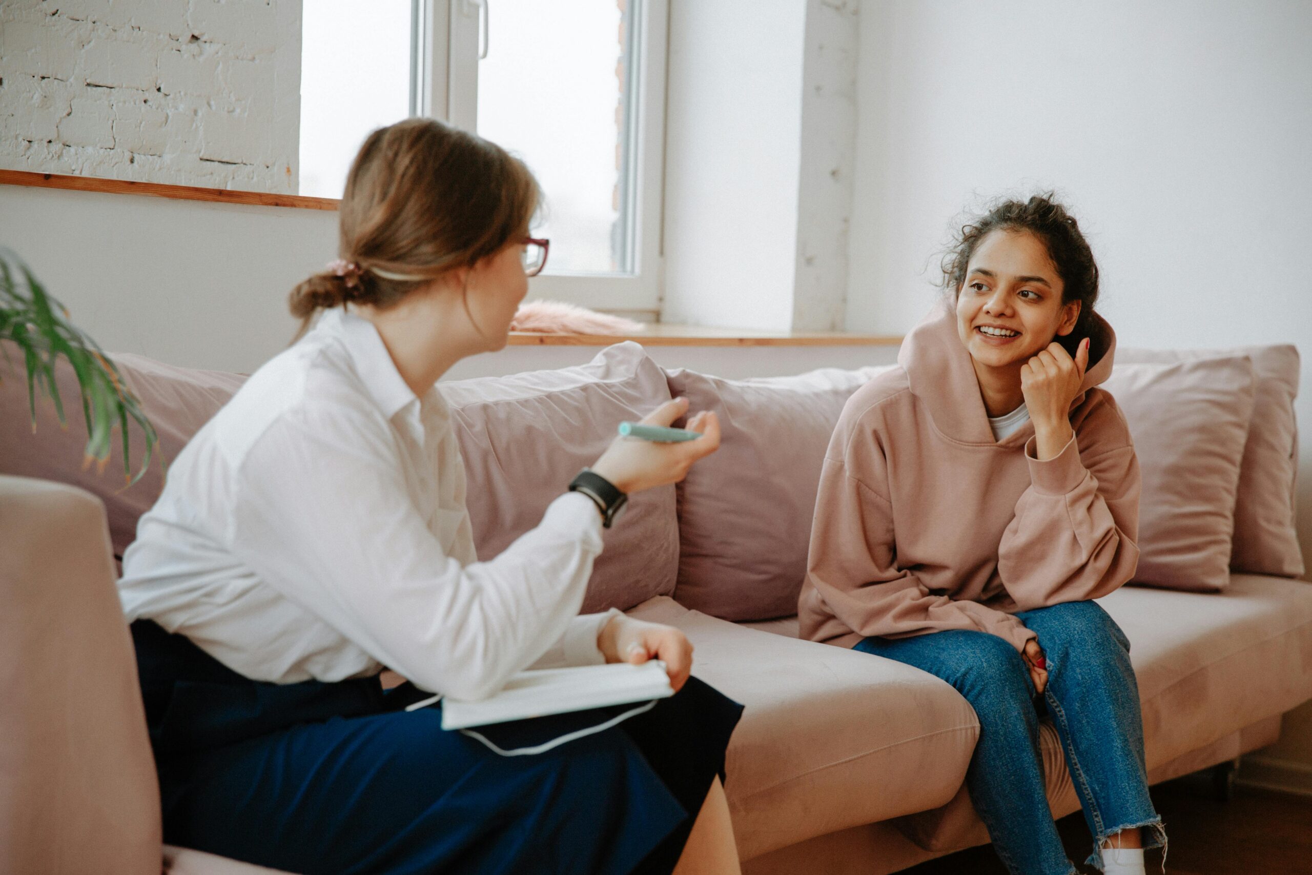 A therapist and young client engaging in a warm counseling session on a cozy sofa.